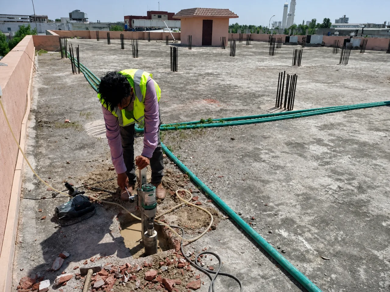 Technician operating concrete coring equipment on a rooftop