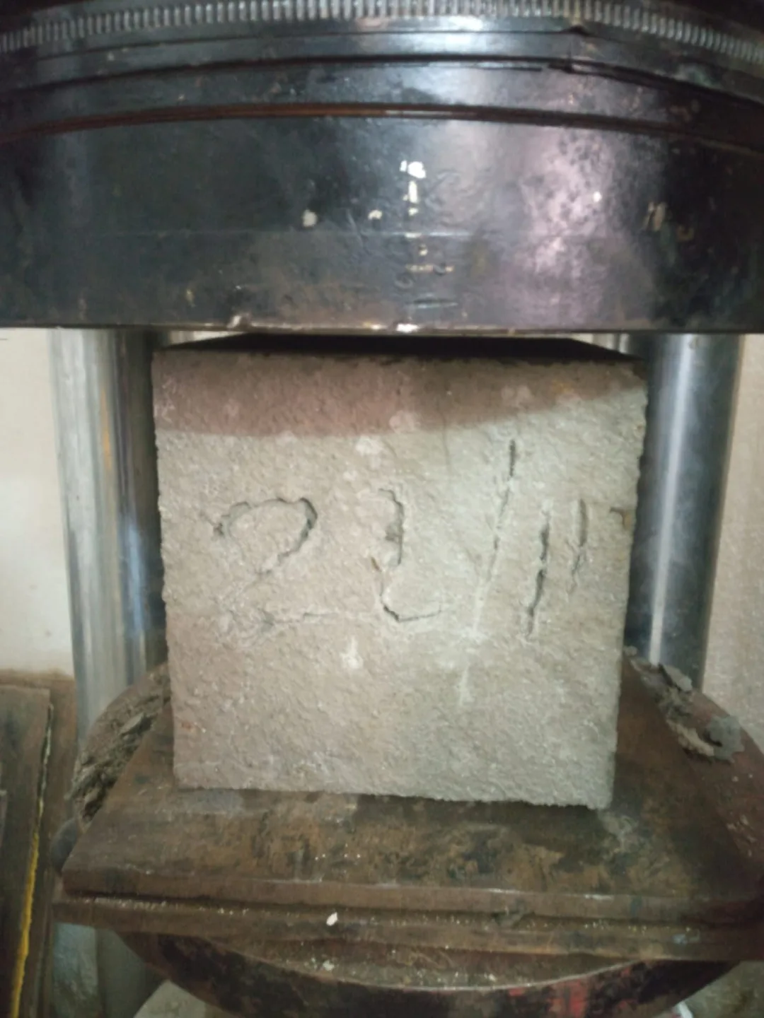 Concrete cube positioned in a compression testing machine