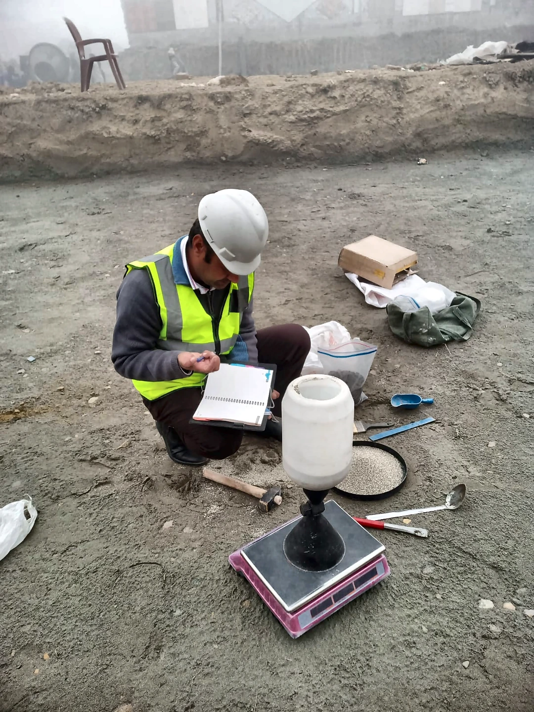 Technician performing a field density test using sand-cone equipment