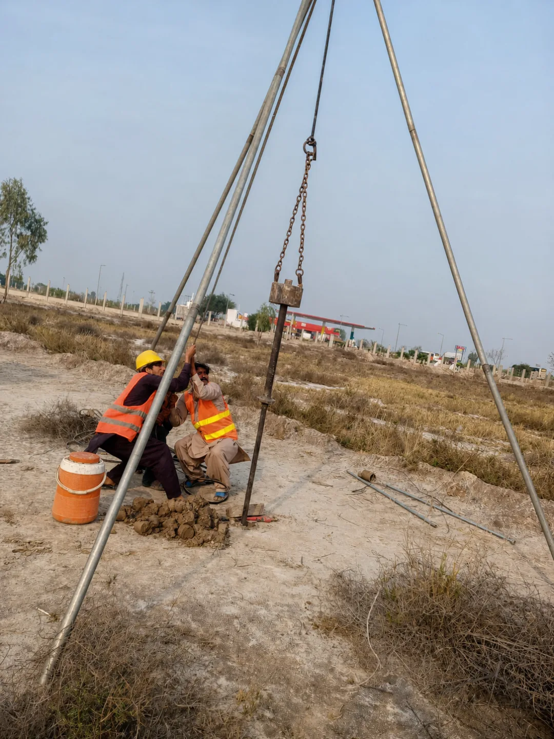 Geotechnical crew operating tripod-supported investigation equipment